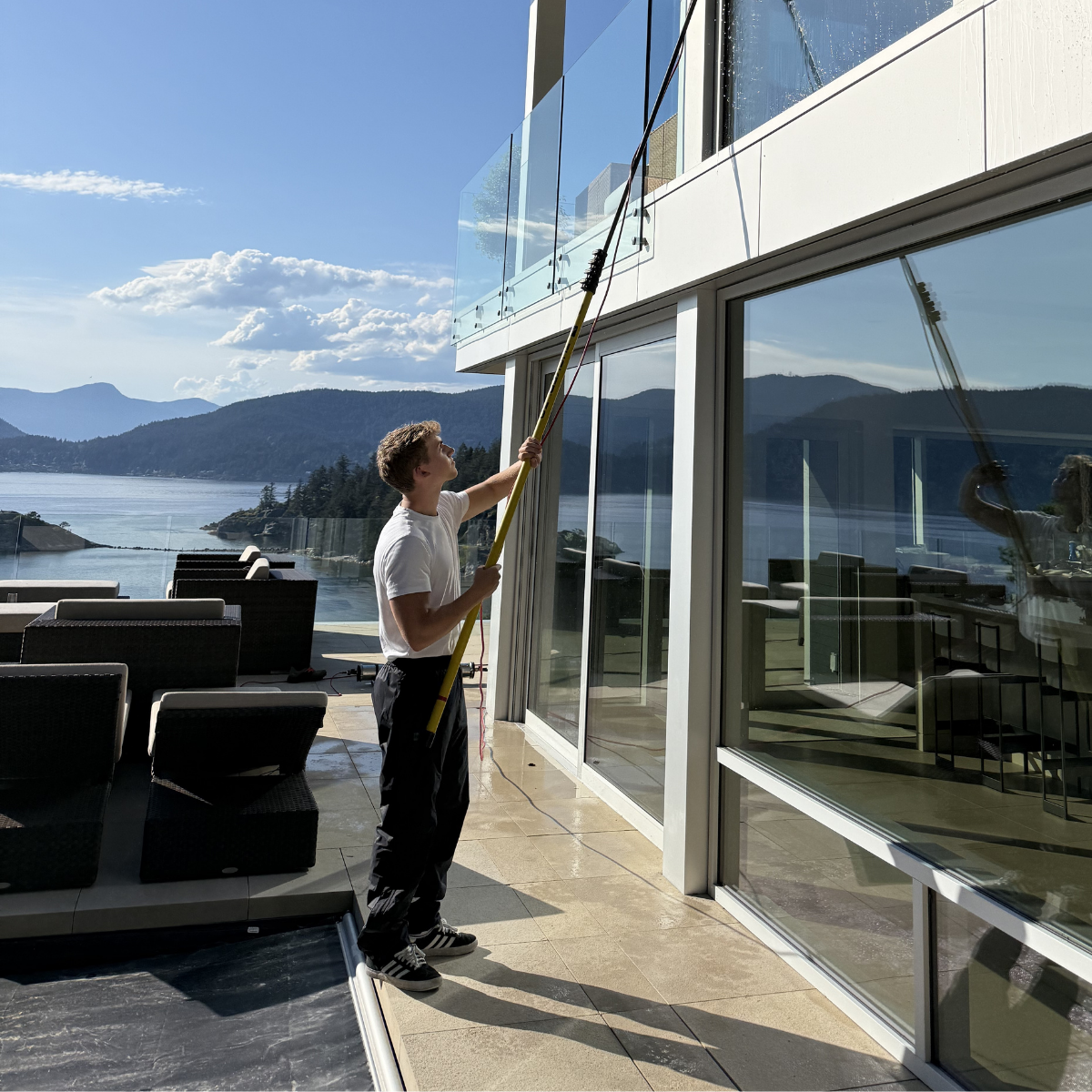 Cody cleaning windows on a luxury North Vancouver home overlooking the water